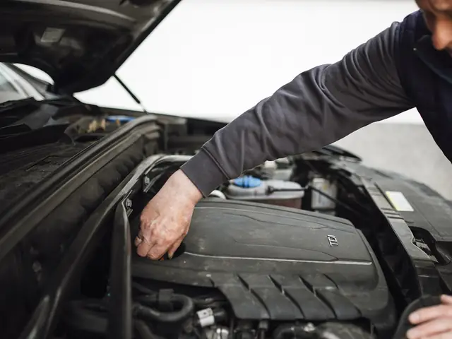 A mechanic working on the engine of a car with the bonnet open