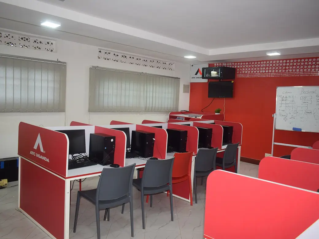 A computer lab with red desks, chairs and monitors