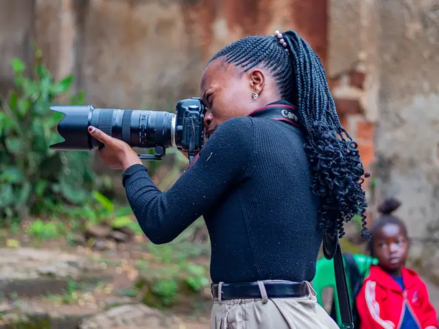 A young photographer aiming a camera with a long lens