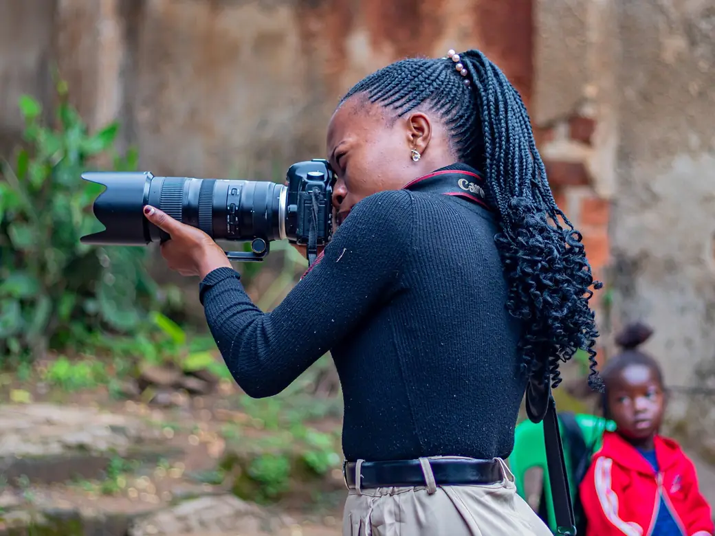 A young photographer aiming a camera with a long lens